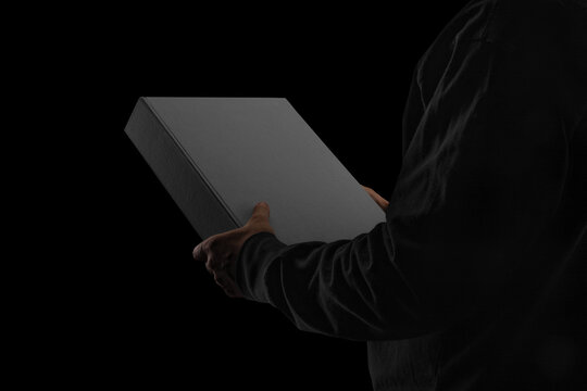 A closed binder box held by a person wearing dark clothing. Minimalistic blackout style with moody, low-key lighting. Perfect for showcasing packaging, premium stationery, branding concepts