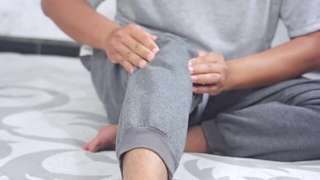 A young man massages his knee due to knee pain and muscle aches caused by Runner's Knee or Patellofemoral Pain Syndrome, osteoarthritis, arthritis, rheumatism, and Patellar Tendinitis. Medical concept