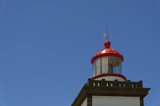 Close-up of a red lighthouse top with compass rose under a clear blue sky, lighthouse Farol da Ferraria, Sao Miguel island, Azores, Portugal