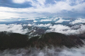 Above the majestic Piatra Craiului Mountains, fog weaves through dense forests as early morning light casts a magical glow on the landscape. This serene scene captivates the soul
