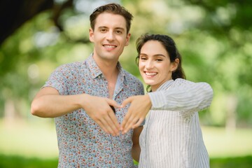 Couple making hand heart gesture in park; customer loyalty, brand care, community support, shared values marketing.