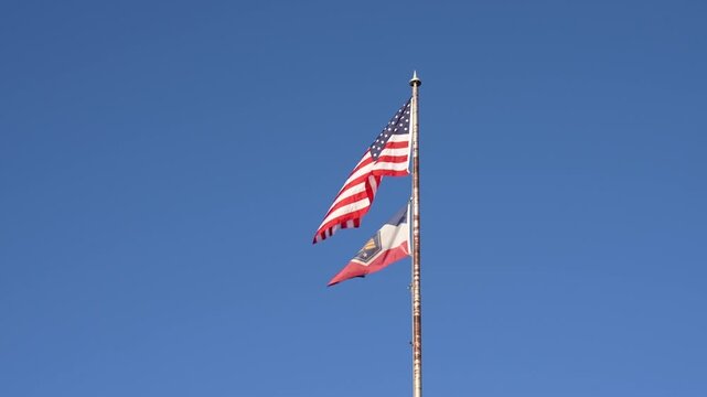 American and Utha flag blowing in the wind on a clear blue sky.