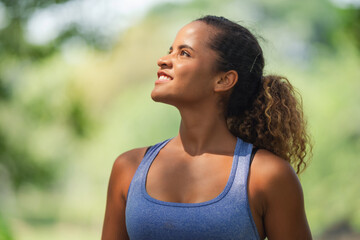 woman looking up and smiling with satisfaction outdoors, optimism, achievement, and mental wellness relief