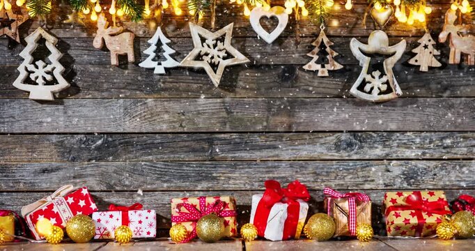 Cozy Christmas decorations arranged on rustic wood with gentle falling snow creating a festive winter atmosphere. Ideal as a holiday background or seasonal backdrop.
