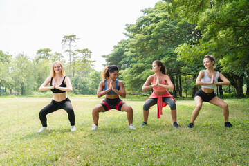Four energized partners perform a synchronized squat pose in a park, unity, collective core strength, discipline, and building a strong foundation.