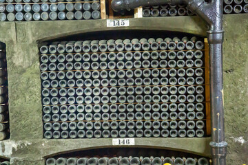 A concrete shelf with bottles of wine in the underground tunnel of the winery. Winemaking viticulture wine blend.