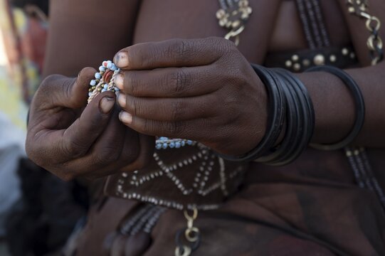 Hands of a Himba woman making bracelets, near Opuwo, Kaokoveld, Kunene, Namibia