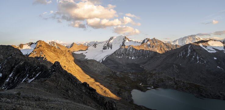 Turquoise mountain lake Ala Kul Lake, mountain peaks with glaciers glowing orage at sunset, Ala Kul Pass, Tien Shan Mountains, Kyrgyzstan