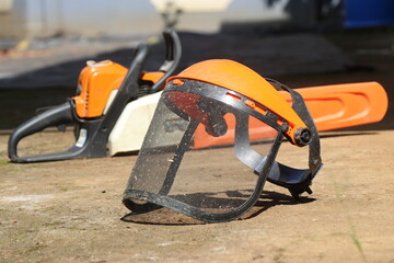 Mesh face shield or full face mesh with chainsaw in the background showing the concept of safety