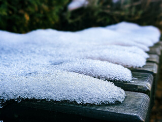 close up fresh first snow and ice crystals texture on wooden bench