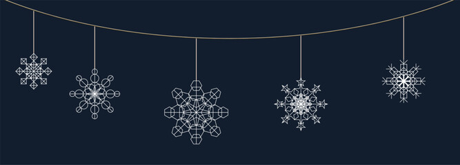 Decorative snowflakes hanging on a string against a dark background during winter festive season