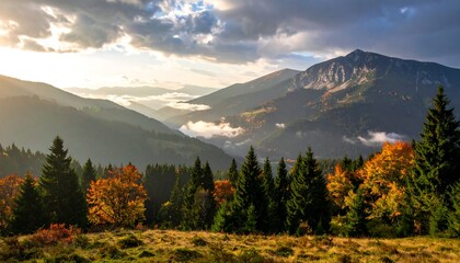 Mountain landscape with fall colors and misty valley under a cloudy, sunset-lit sky