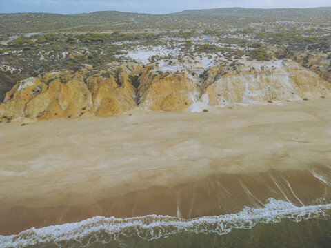 Aerial view of the Playa Torre del Loro where golden cliffs meet the sea, creating a stunning contrast of colors and textures, Mazagon, Andalusia, Spain.