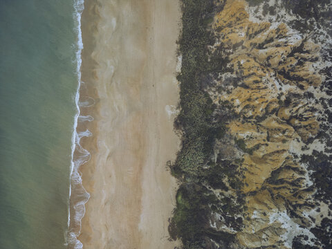 Aerial view of the Torre del Loro beach where the turquoise sea meets the golden sands, bordered by rugged cliffs, Mazagon, Andalusia, Spain.