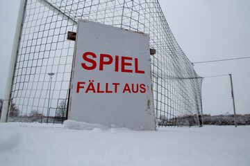 Symbolbild Spielabsage im Fu&szlig;ball wegen Schnee. Schild auf einem Sportplatz mit der Aufschrift SPIEL F&Auml;LLT AUS