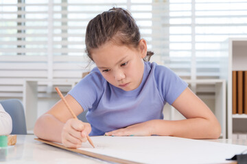 Caucasian elementary girl student leaning desk concentrating on drawing paper with pencil during classroom art lesson representing diligence creativity educational growth artistic exploration