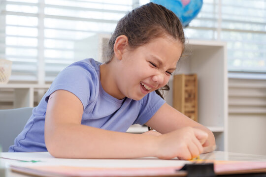 Caucasian preteen girl laughing joyfully while pressing crayon on notebook during art lesson classroom activity elementary education creativity friendship fun diligence concentration achievement