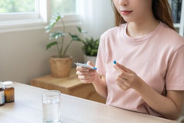Sick ill asian young woman, girl hand taking tablet pill capsule out from blister pack, painkiller...