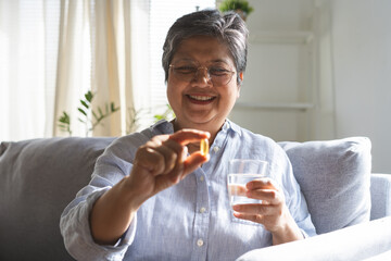 Dietary supplement health care concept, happy smile asian senior woman hand holding fish oil pills,...