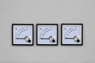 A row of three square measuring instruments for current control on a gray background