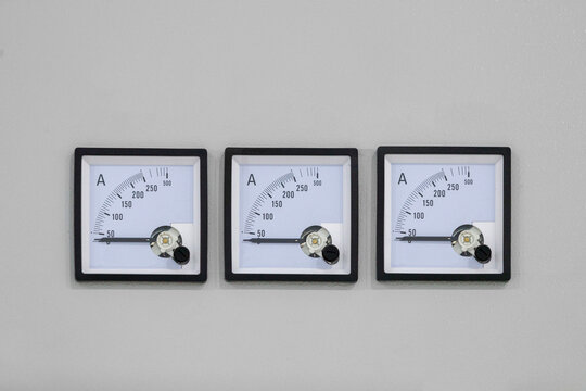 A row of three square measuring instruments for current control on a gray background