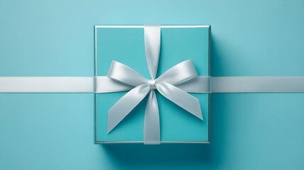 Minimalist shot of elegant teal square gift box with shiny silver ribbon bow placed on solid color backdrop creating festive atmosphere
