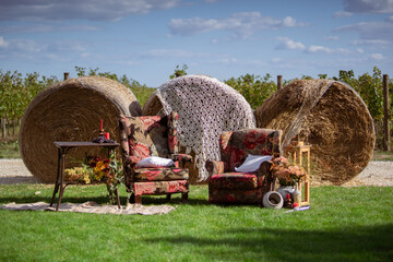 Rustic Outdoor Lounge Setup With Vintage Armchairs and Hay Bales