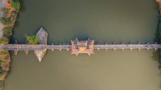 Aerial view of the ancient bridge with intricate tiled roofs spanning the river's calm waters, Honghe Hani and Yi Autonomous Prefecture, Yunnan, China.