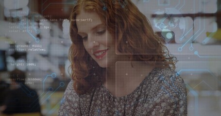 Smiling woman with curly red hair wearing patterned blouse reading code at cafe, digital overlays