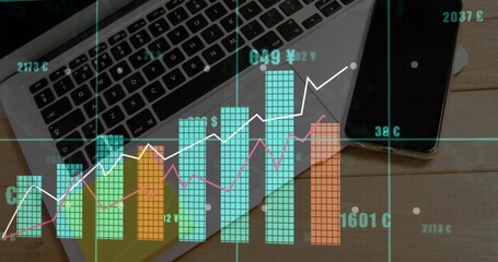 Displaying multicolored financial data visualization over work desk, with laptop and smartphone