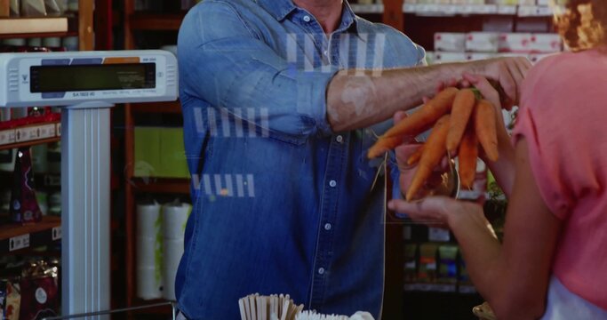 Handing vendor in denim passing carrots at market checkout, woman in pink top receiving with scale - Powered by Adobe