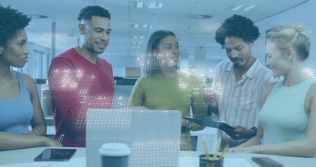 Collaborating team in business casual leaning over laptop in open-plan office, holding tablet