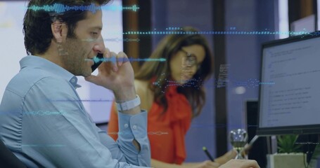 Talking blue-shirt man on phone, viewing code monitor at desk, red-clad woman noting waveform