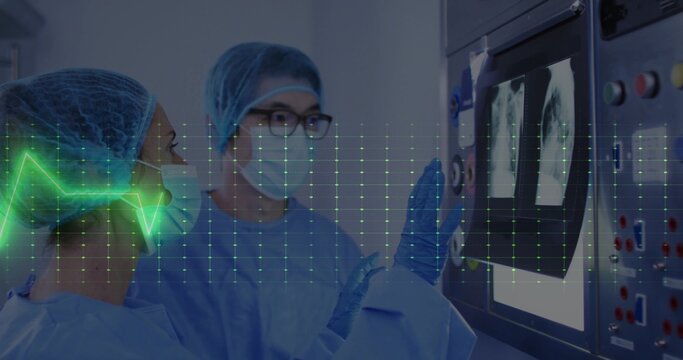 Focusing two clinicians in blue gowns studying chest X-rays at hospital console, with ECG overlay