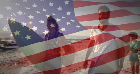 Walking four friends in beachwear carrying surfboards on sandy shore in late light, US flag overlay