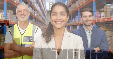 Posing supervisor in light blazer centered in warehouse with racking, team in vest and suit