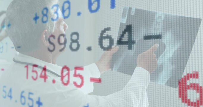 Pointing senior doctor examining X-ray in radiology, in lab coat and stethoscope, numeric overlay - Powered by Adobe