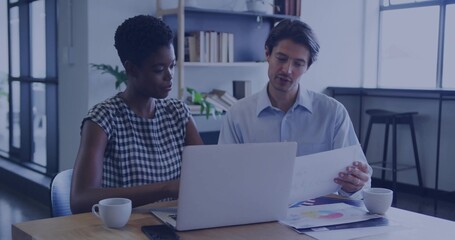 Discussing woman checked dress man light blue shirt reviewing laptop and color charts office table