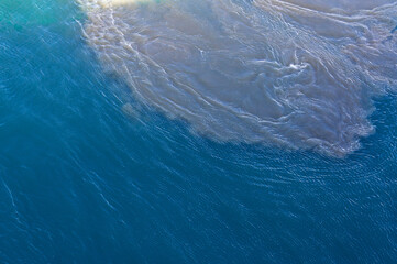 Dirty slag and oily water stirred up by ship propellers in the container port. Environmental pollution caused by heavy fuel oil from the container shipping industry and transport.	