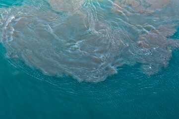 Dirty slag and oily water stirred up by ship propellers in the container port. Environmental pollution caused by heavy fuel oil from the container shipping industry and transport.	