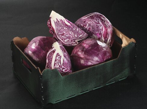 A charming green basket holds fresh, vibrant red cabbage, showcasing intricate patterns and deep purple hues. This scene invites creativity in cooking with seasonal vegetables
