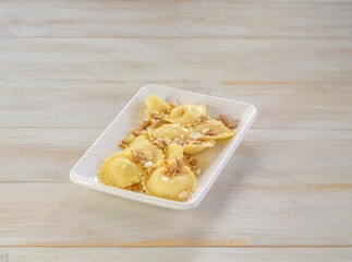 A plate of freshly prepared Griasoli Pasta is elegantly presented with a sprinkle of crushed nuts on top. The setting is warm and inviting, perfect for a delightful meal