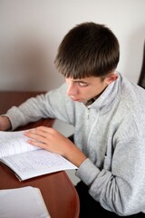 Focused student engaged in studying diligently at a wooden desk in a bright room during the late afternoon, demonstrating the essence of learning and dedication to education