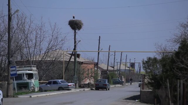 View from a moving vehicle showing a lake with a water tower in rainy weather and a winding mountain road with a sharp turn warning sign.

