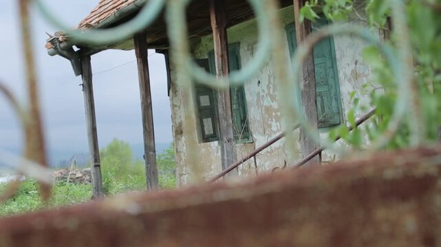 View from a moving vehicle showing a lake with a water tower in rainy weather and a winding mountain road with a sharp turn warning sign.

