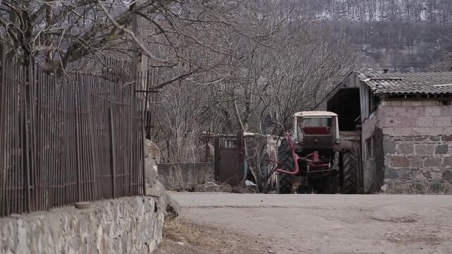 View from a moving vehicle showing a lake with a water tower in rainy weather and a winding mountain road with a sharp turn warning sign.


