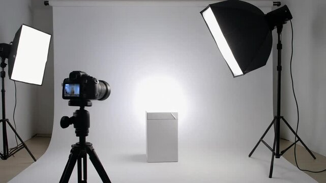 Professional photo studio setup with a camera, tripod, and lighting equipment for product photography on a white background.