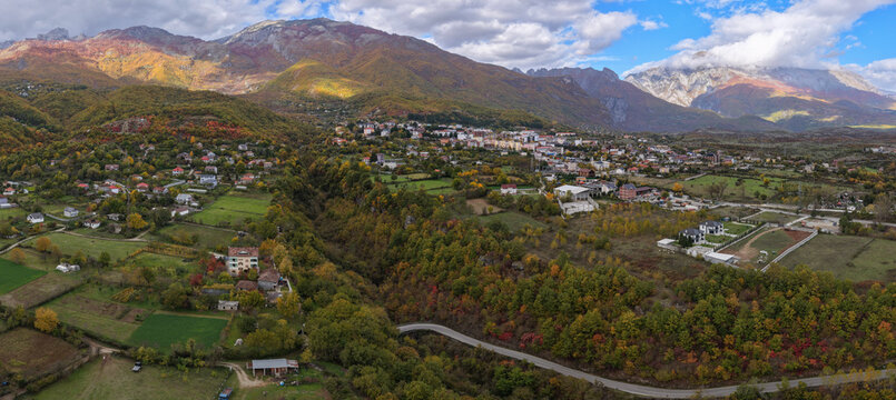 Panoramic view of Bajram Curri surrounded by autumn forests, farmland and dramatic alpine mountain slopes.