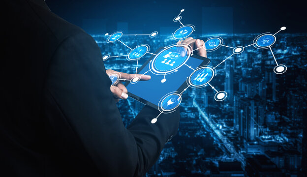 A business professional interacts with a futuristic digital interface on a tablet, showcasing virtual data visuals against a vibrant city skyline in the background. Tessel