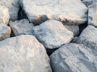 Close-up shot of large natural rocks with rough textures and earthy tones, captured in soft daylight, showing details of stone surfaces and rugged formations.
